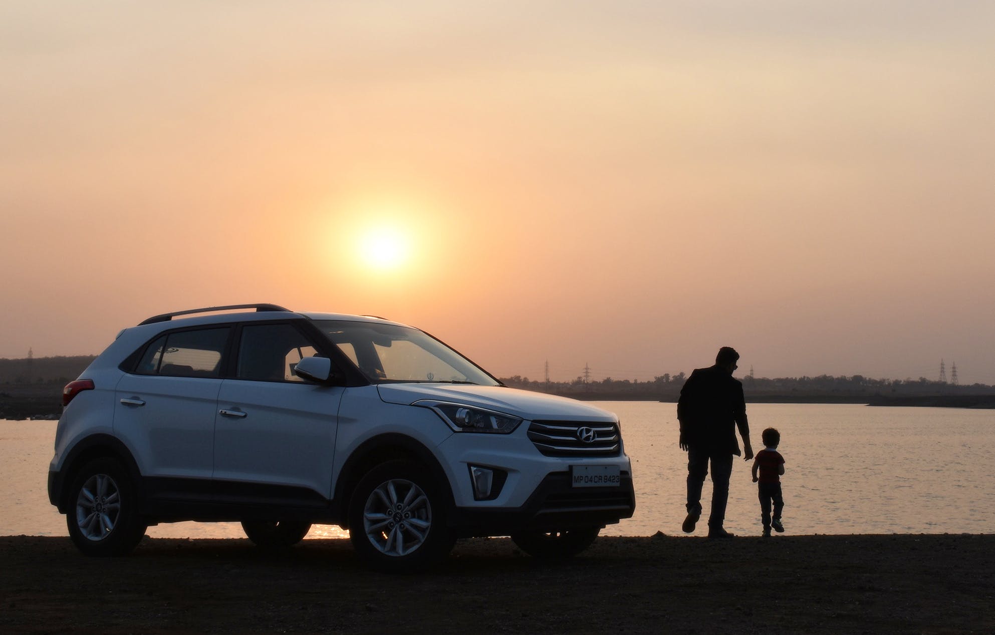 Father and child next to a car at sunset