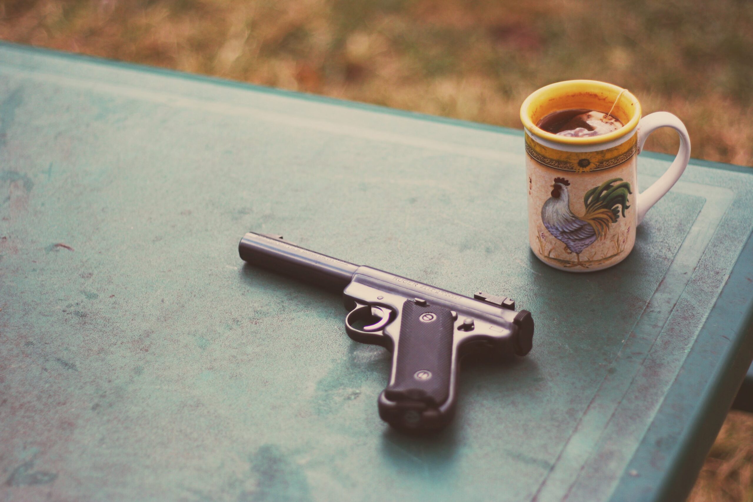 A handgun on a table, next to a mug